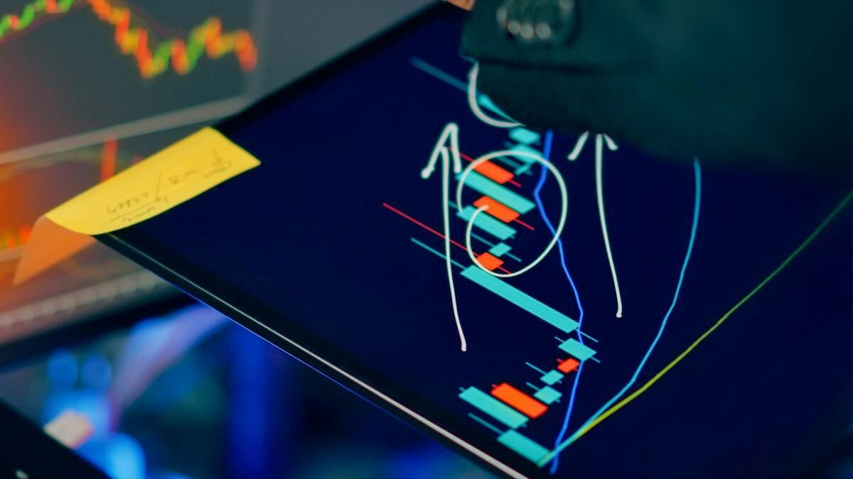 Inwestor analizujący wykresy na ekranach tabletu i laptopa