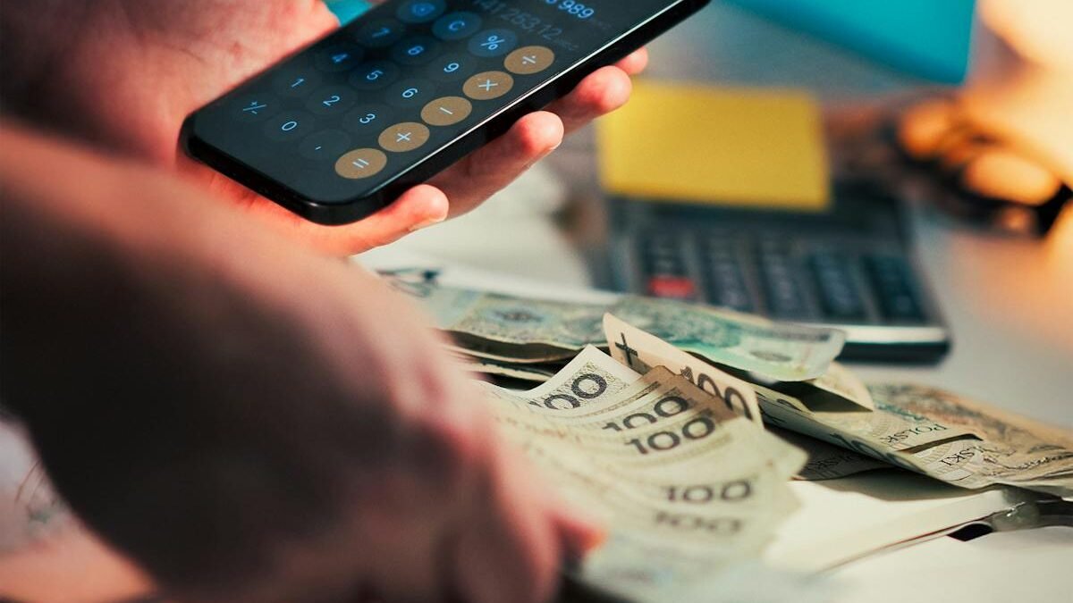 Osoba obliczająca finanse za pomocą smartfona i gotówki