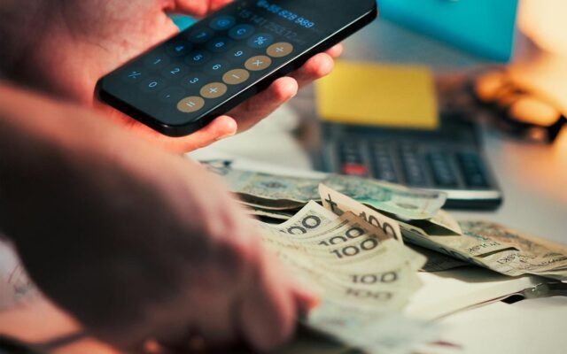 Osoba obliczająca finanse za pomocą smartfona i gotówki