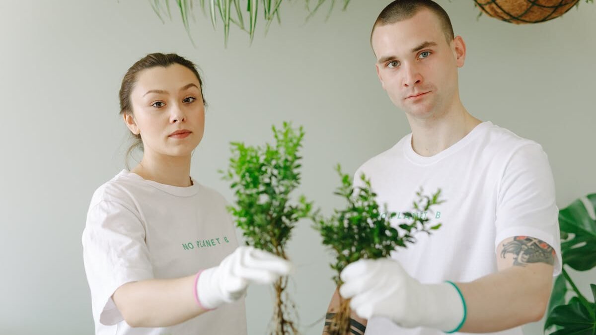 Mężczyzna w białym t-shircie trzymający zieloną roślinę