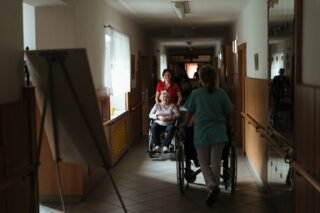 Opiekunowie pchający wózki inwalidzkie z seniorami
