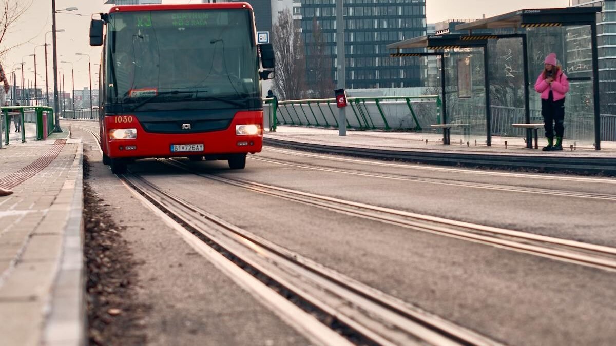 Miejski przystanek tramwajowy z czerwonym autobusem i widokiem na miasto