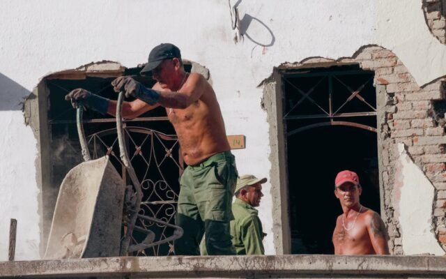 Mężczyźni bez koszulek pracujący na balkonie starego budynku